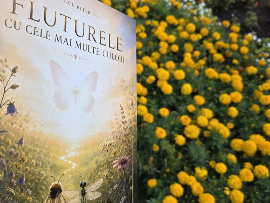 Cartea Fluturele cu cele mai multe culori fotografiată printre flori